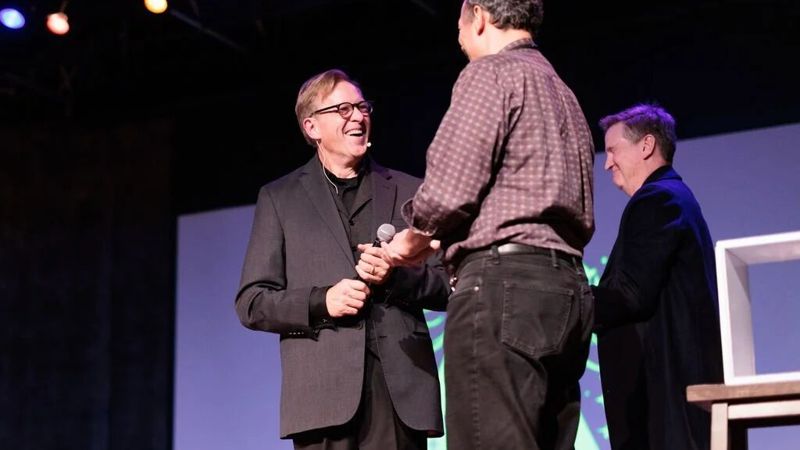 Rich Crawford on stage with an audience volunteer during a corporate magic show