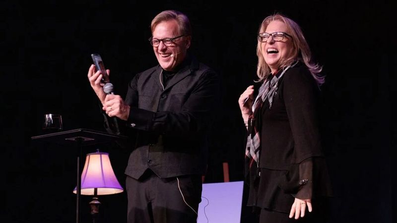 Rich Crawford and an audience volunteer laughing on stage during a mentalism show