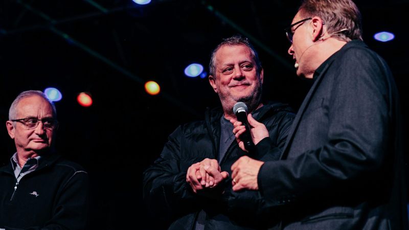 Rich Crawford on stage with two audience volunteers at a corporate event