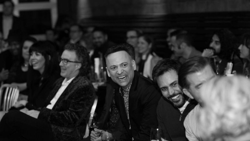 Corporate guests laughing together during a magic show, black and white photo