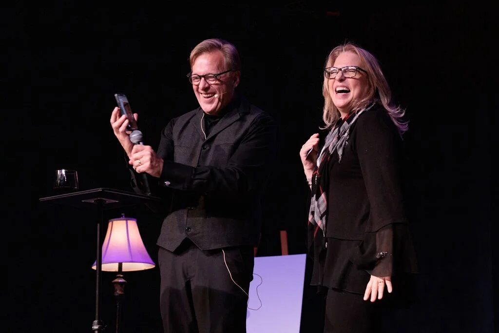 Rich Crawford and an audience volunteer laughing on stage during a mentalism show