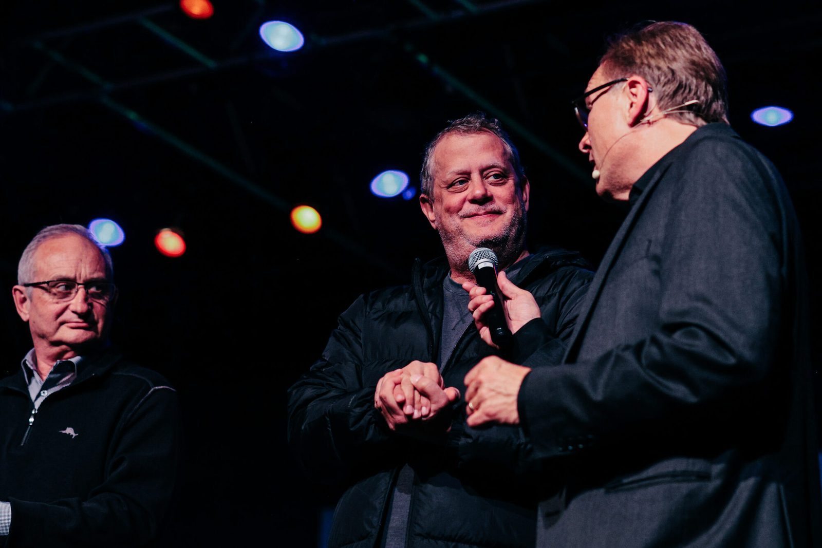 Rich Crawford on stage with two audience volunteers at a corporate event
