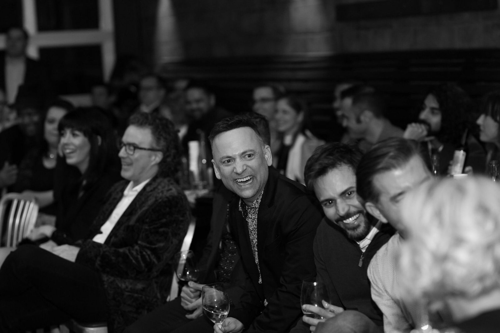 Corporate guests laughing together during a magic show, black and white photo